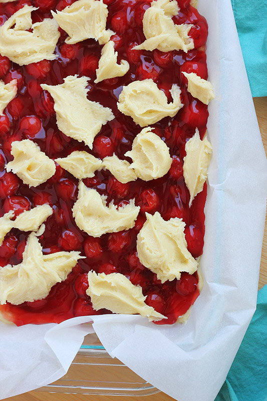 cherry pie filling spread in a pan with dots of dough on top