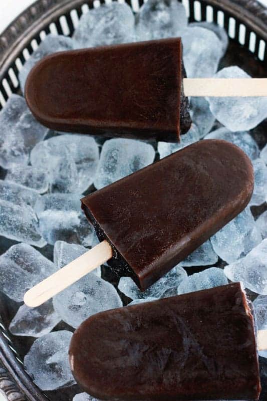 three chocolate ice pops on a tray of ice