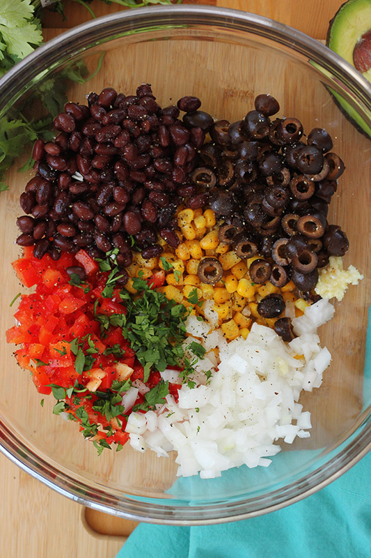 bowl of salsa ingredients sitting on a wooden table 