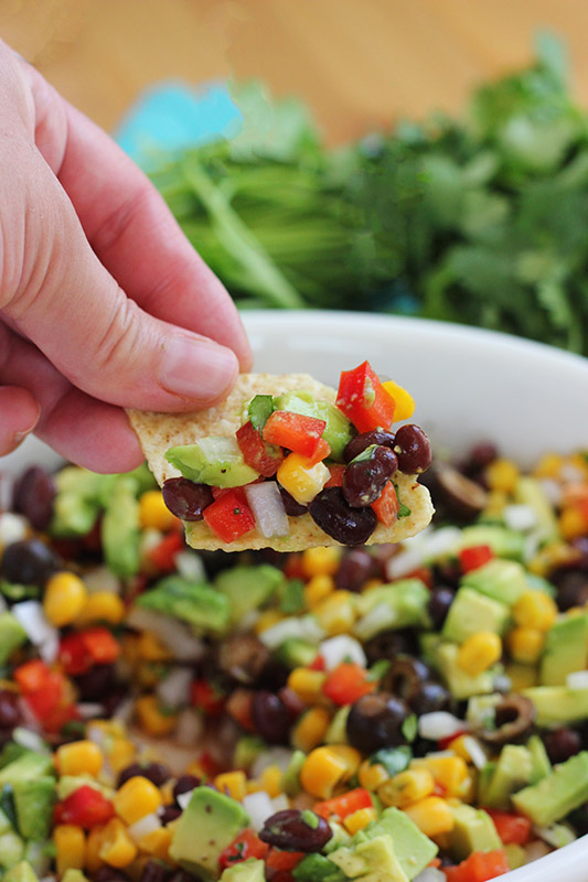 chip scooping salsa out of a white dish