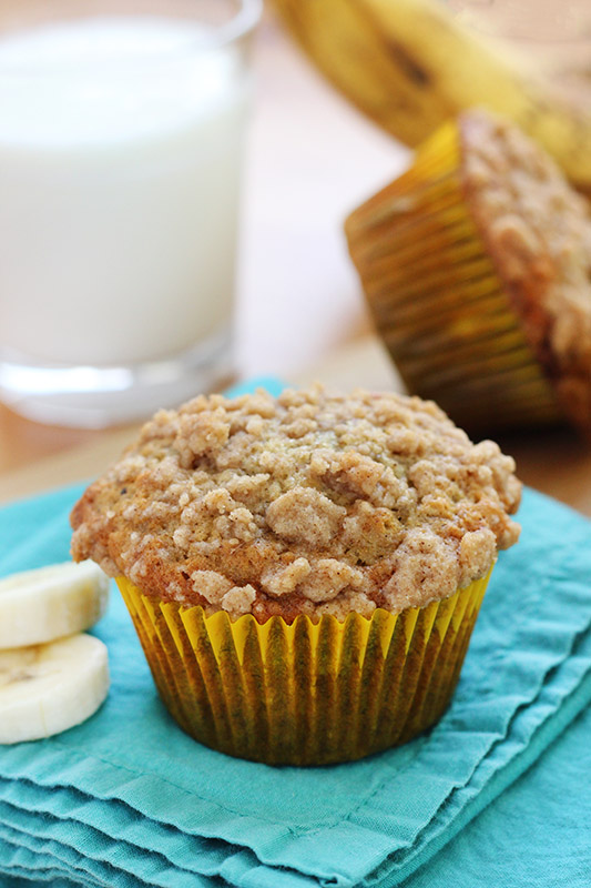 Single banana bread muffin in a yellow liner sitting on a teal napkin