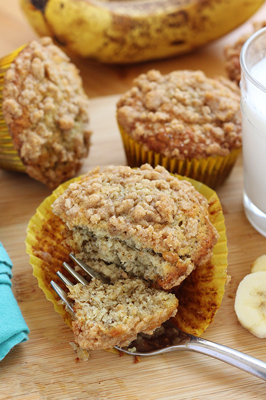 banana muffin sitting on a wooden table with a bite on a fork