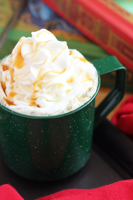 close image of a latte in a green glass with whipped cream