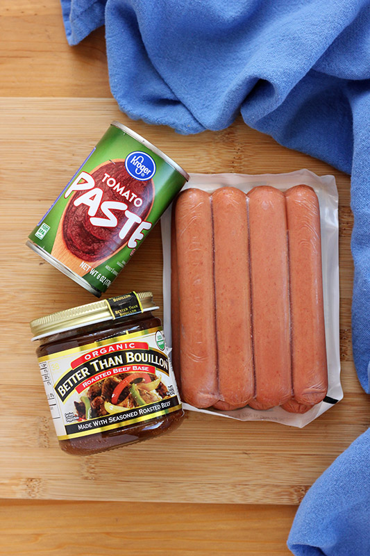 hot dogs, better than bouillion, and tomato paste on a wooden cutting board