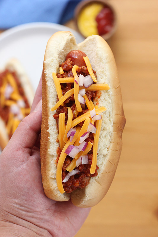 hand holding a chili dog