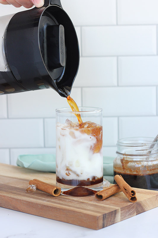 coffee being poured into a glass with dolce syrup and milk