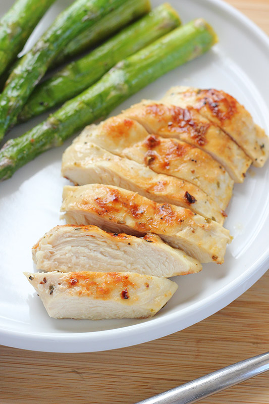 sliced chicken breast on a white plate with asparagus