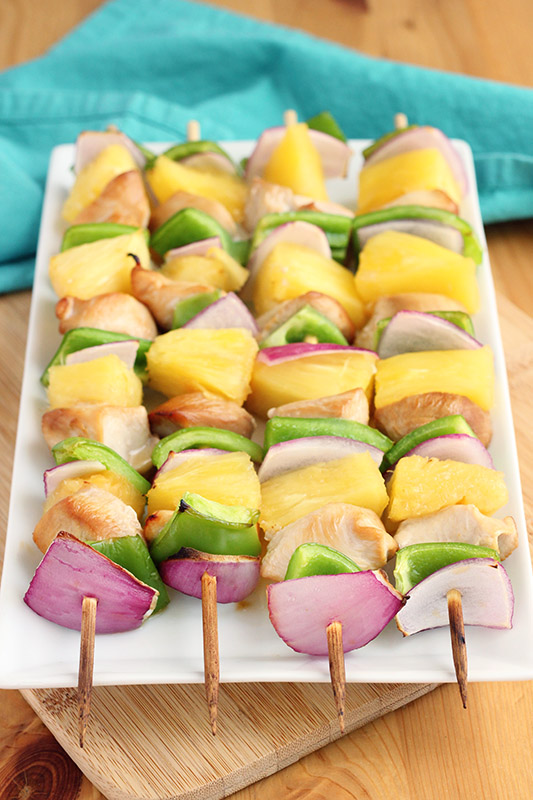 White plate layered with cooked chicken kabobs