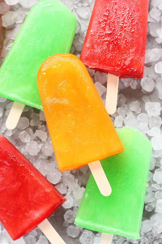 stack of colorful popsicles on a tray filled with ice