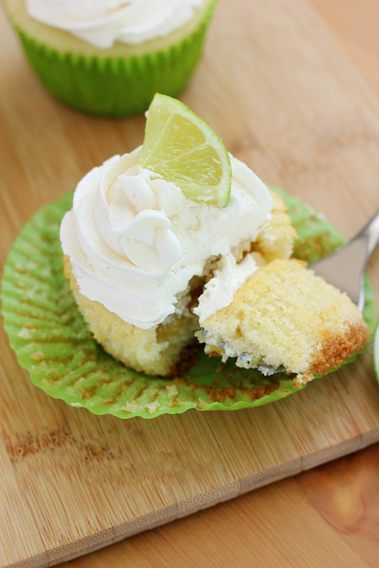 close up photo of a lime cupcake with a bite sitting on a fork