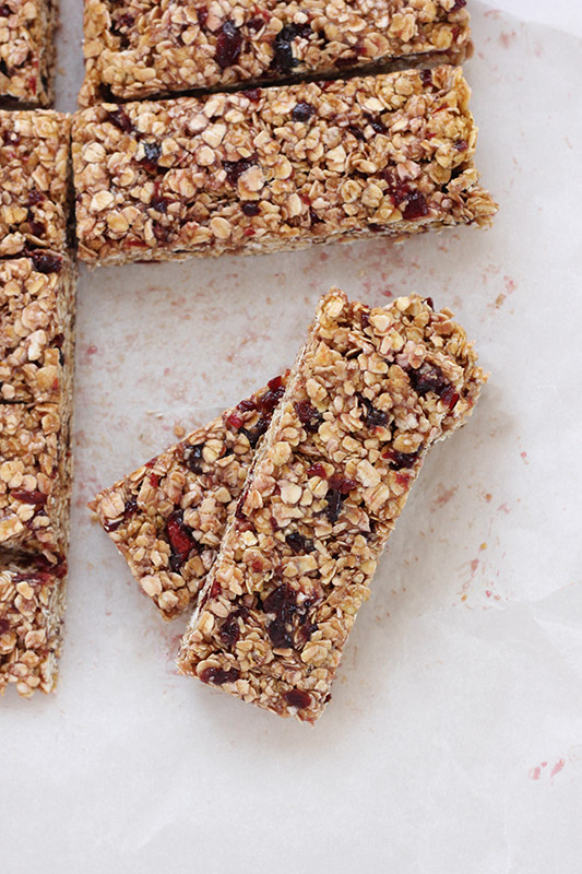 two peanut butter and jelly granola bars stacked on white parchment paper