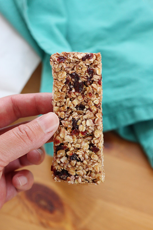 hand holding a single granola bar filled with dried cranberries