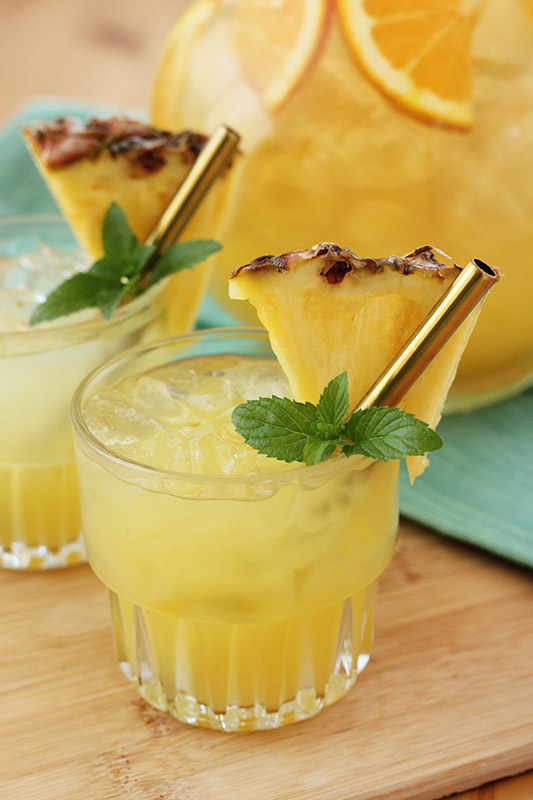Glass filled with punch and topped with a slice of fresh pineapple