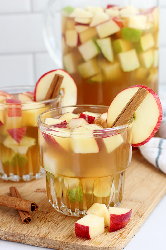 apple sangria in a glass filled with apple pieces and cinnamon sticks