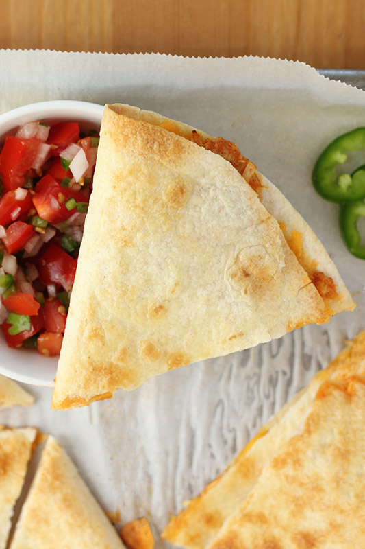 triangle quesadilla resting on top of a bowl of pico