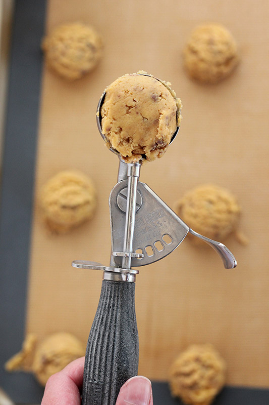 cookie dough in a cookie scoop over a baking tray