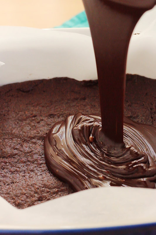 chocolate pouring over the top of baked brownies