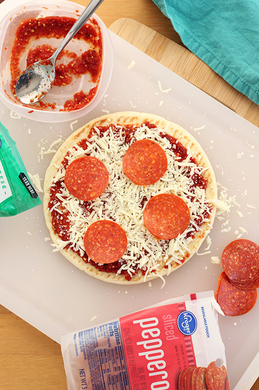 pizza being built on a white cutting board