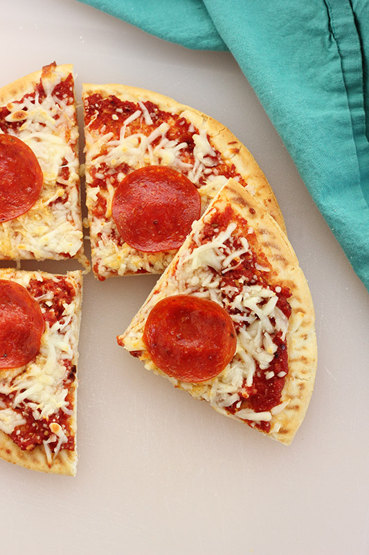 mini pizza on a white cutting board cut into 4 pieces 