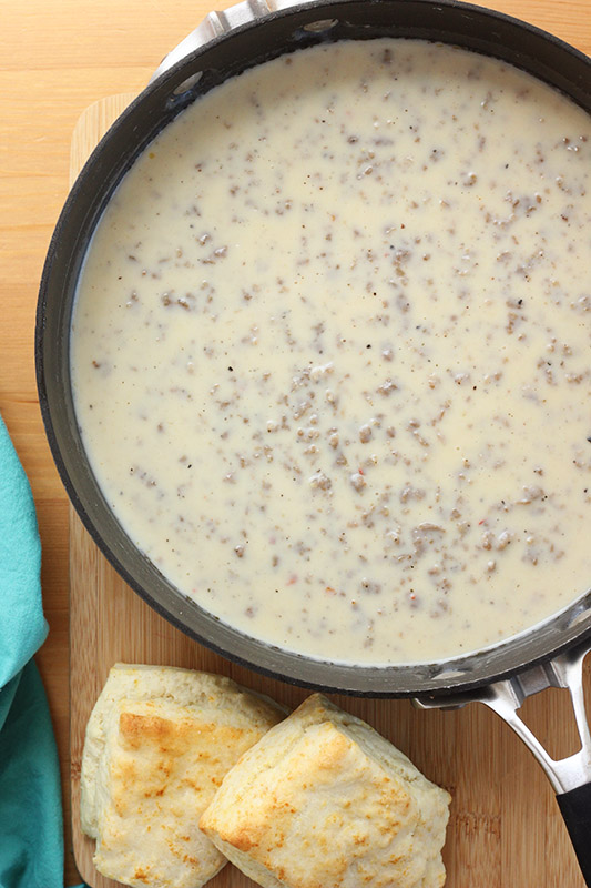 skillet filled with sausage gravy and a side of biscuits