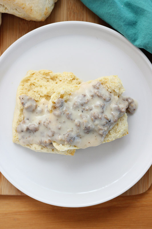 open biscuit smothered in sausage gravy on a white plate