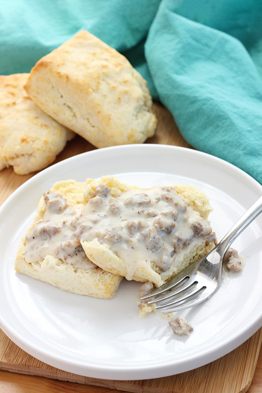 split biscuit smothered in gravy on a white plate with a fork