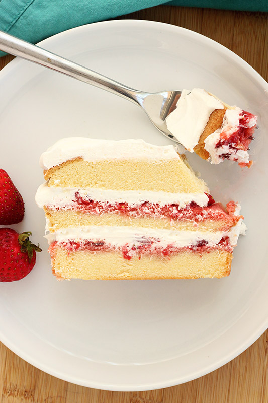 slice of strawberry no-bake cake with a bite on a fork on a white plate