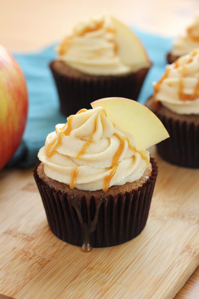 single cupcake drizzled with caramel and topped with an apple slice