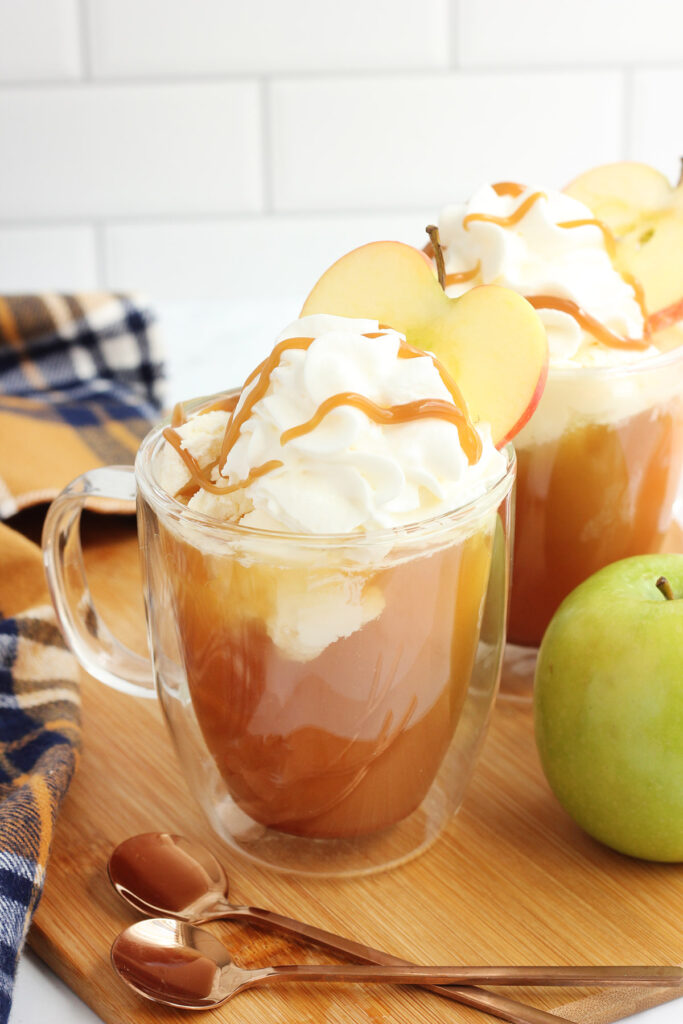 glass mug filled with cider and a scoop of ice cream with apple slices on top