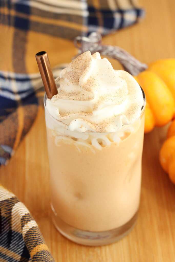 close up image of a milkshake in a glass topped with whipped cream and a gold straw