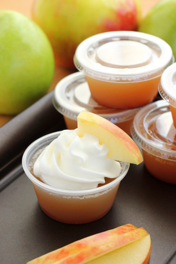 apple pie jello shot topped with whipped cream and a fresh apple