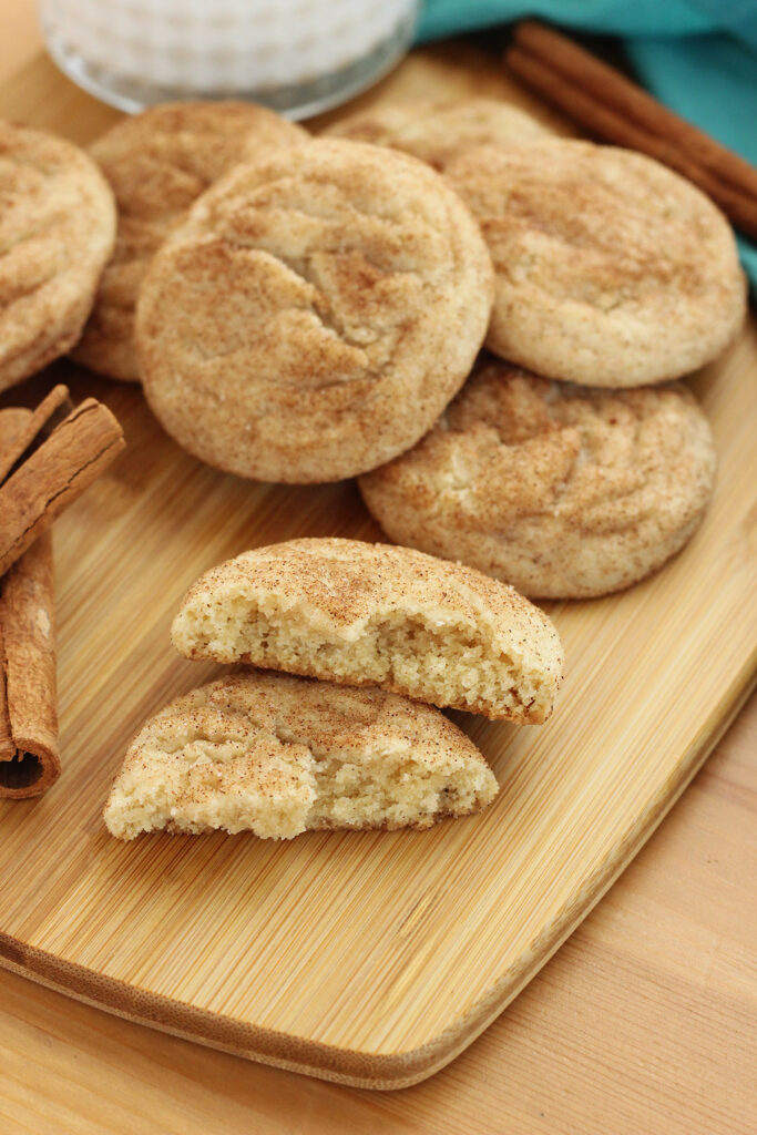 stack of cinnamon and sugar cookies on a wooden cutting board with one broken in half