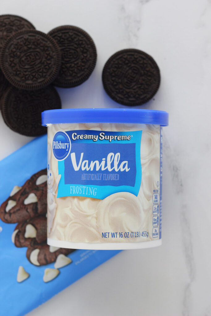 vanilla frosting and chocolate cookies on a white table