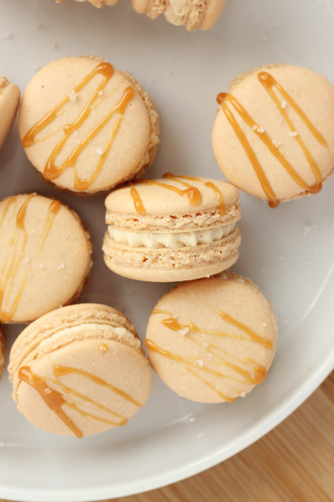 close up image of a macaron with a caramel drizzle on a white plate