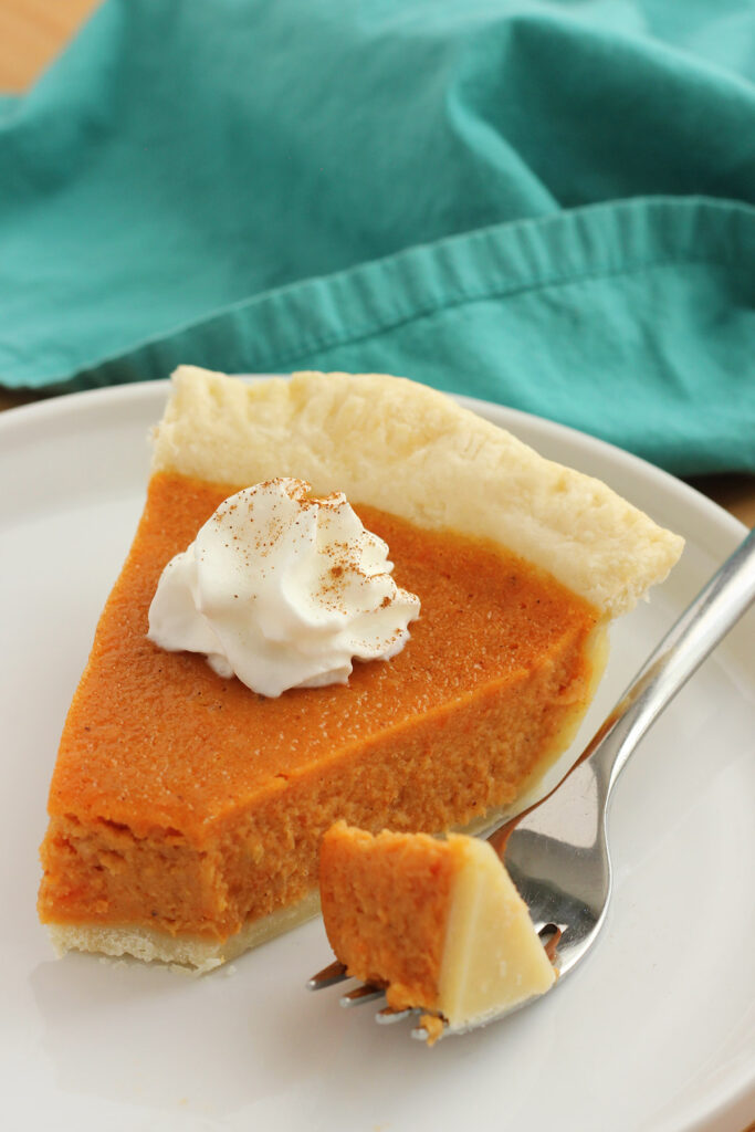 close up image of a slice of sweet potato pie with whipped cream