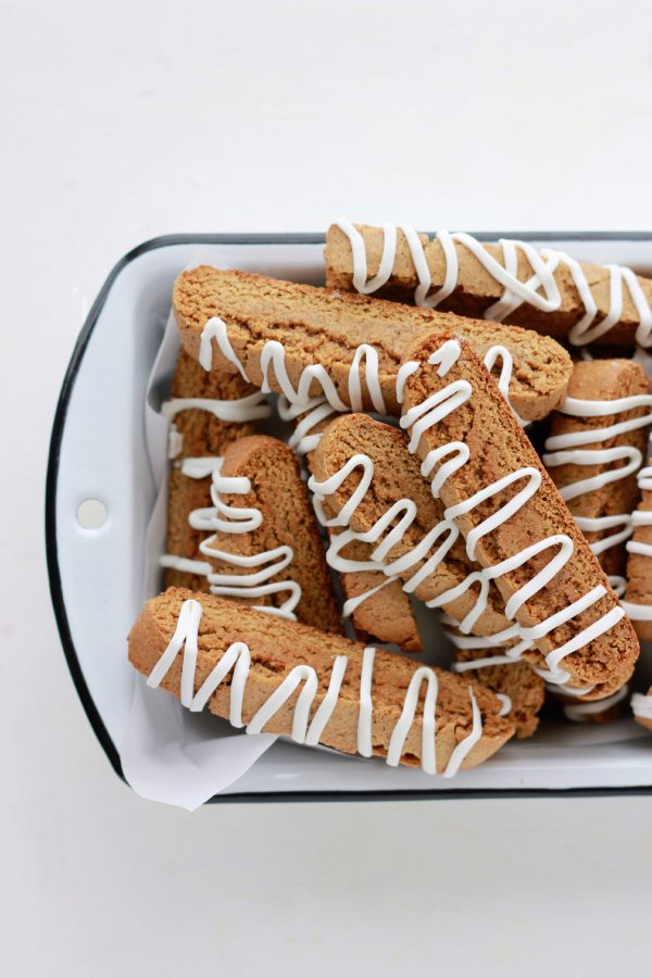 white bread pan filled with crispy biscotti topped with white frosting