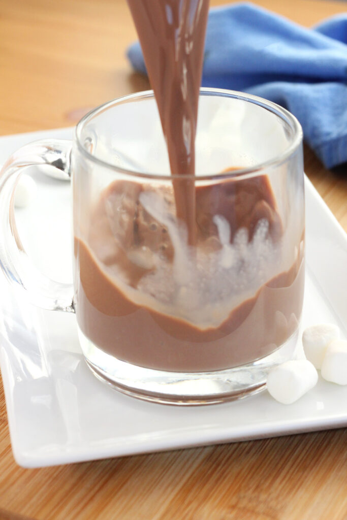 cocoa being poured into a clear mug