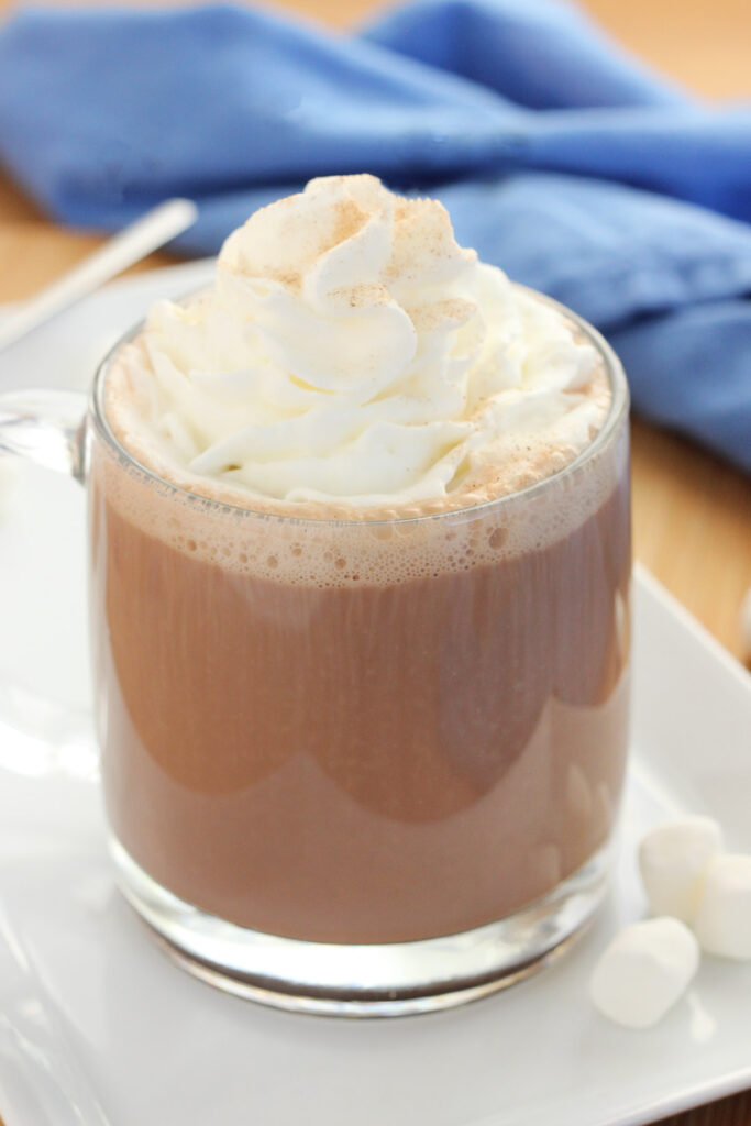 glass mug filled with cocoa that has been topped with whipped cream