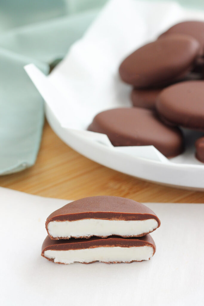 peppermint candy cut in half with a white filling on a white piece of parchment paper. 