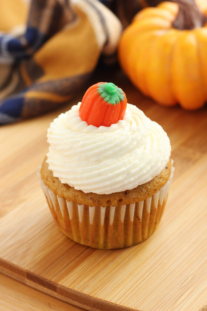 pumpkin cupcake topped with cream cheese frosting and a candy pumpkin
