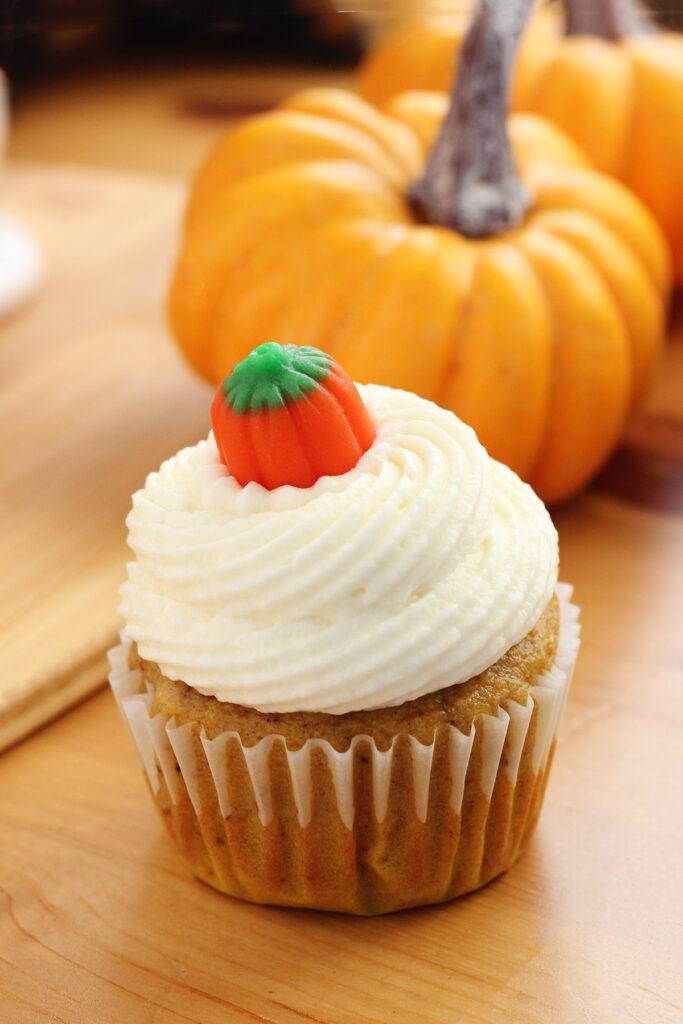 pumpkin spice cupcake topped with frosting and a pumpkin candy