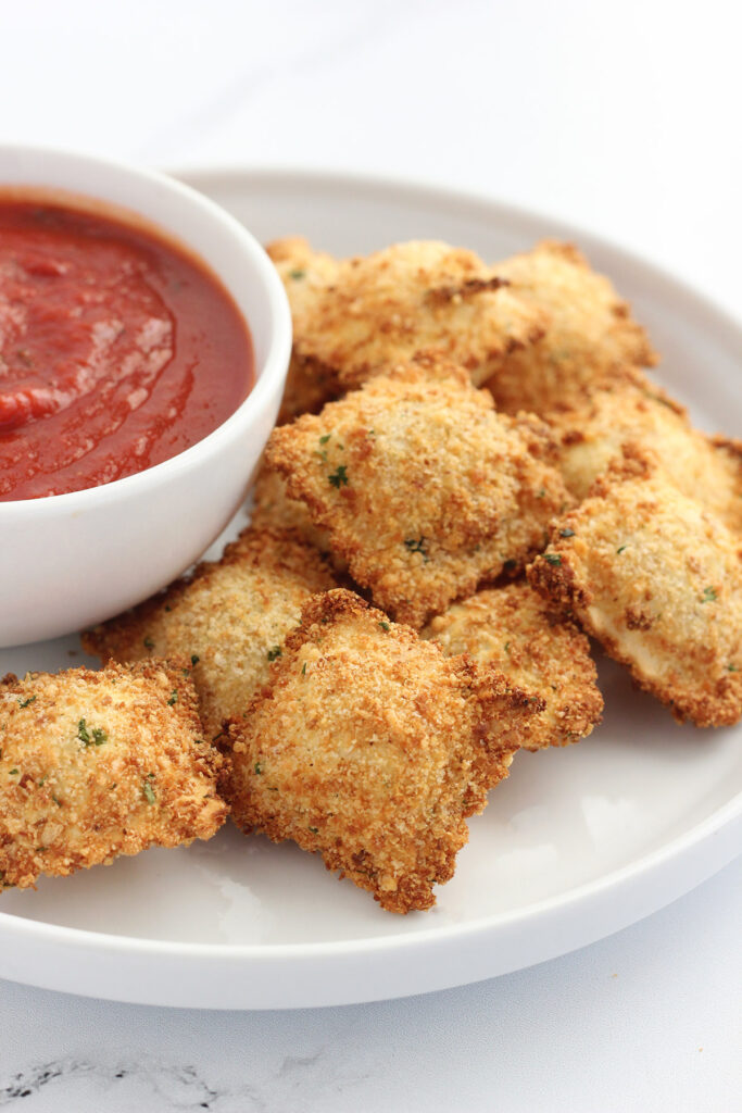 plate stacked with toasted ravioli and dipping sauce