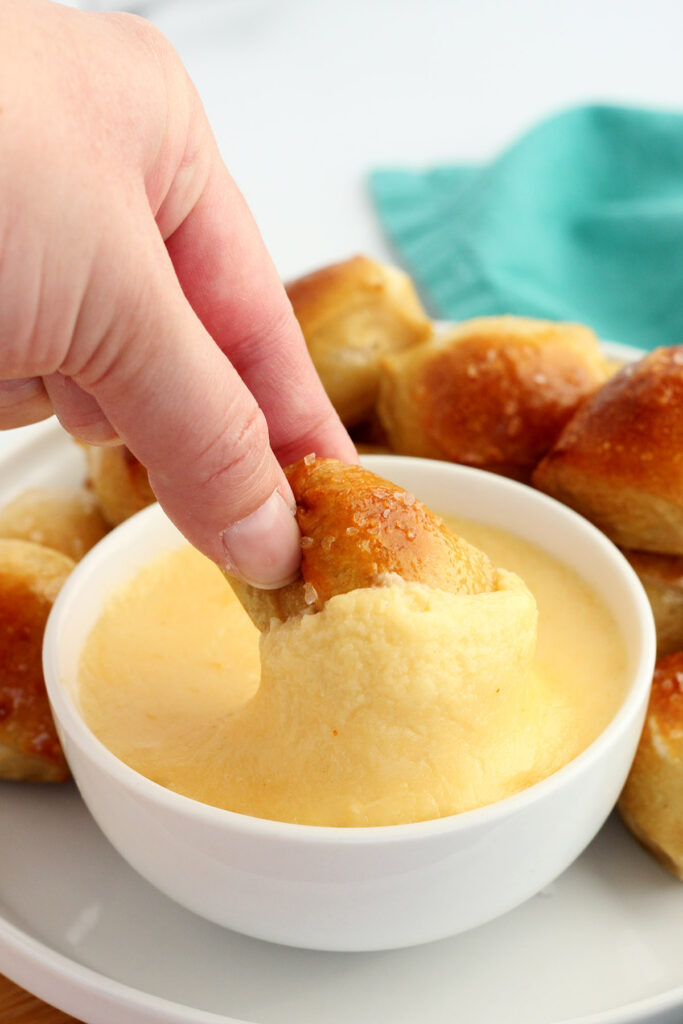 small pretzel being dipped in cheese