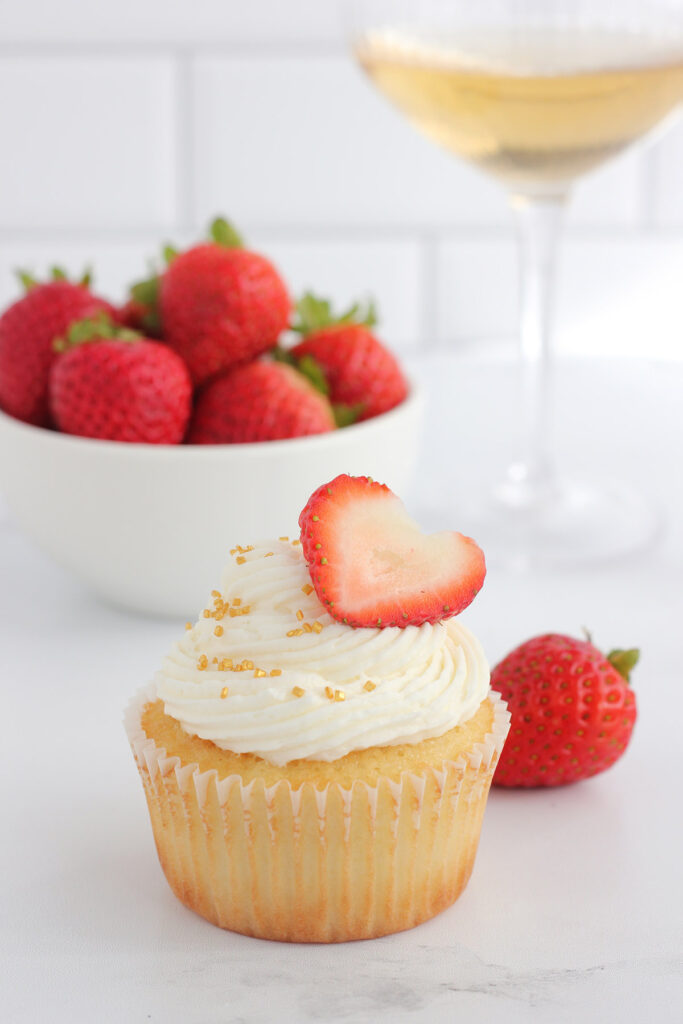 single cupcake in a white wrapper with a slice of strawberry on top of white buttercream