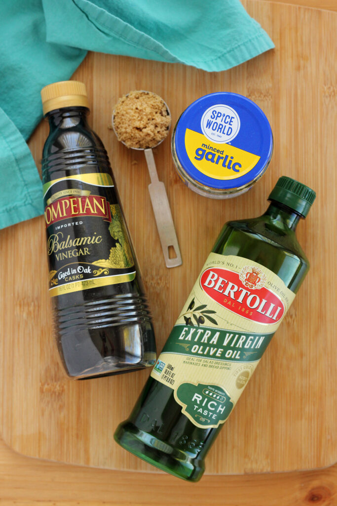 ingredients for vinaigrette on a wooden cutting board with a teal napkin