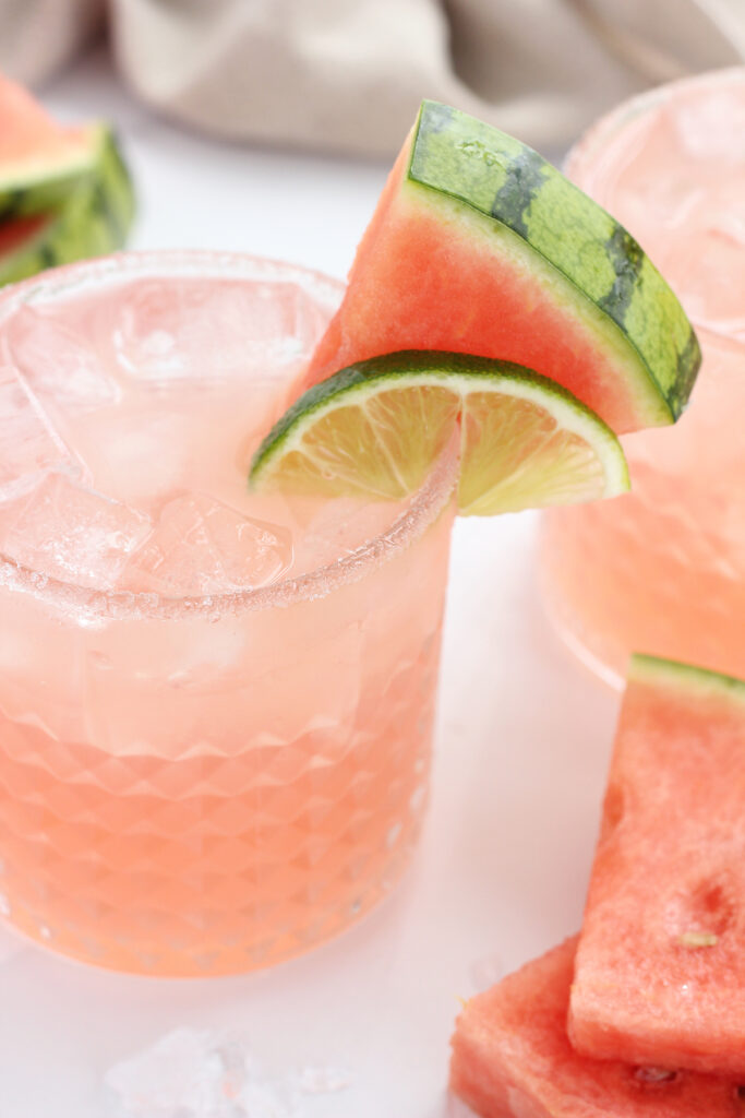 close up image of a glass that is rimmed with sugar and filled with a pink watermelon cocktail