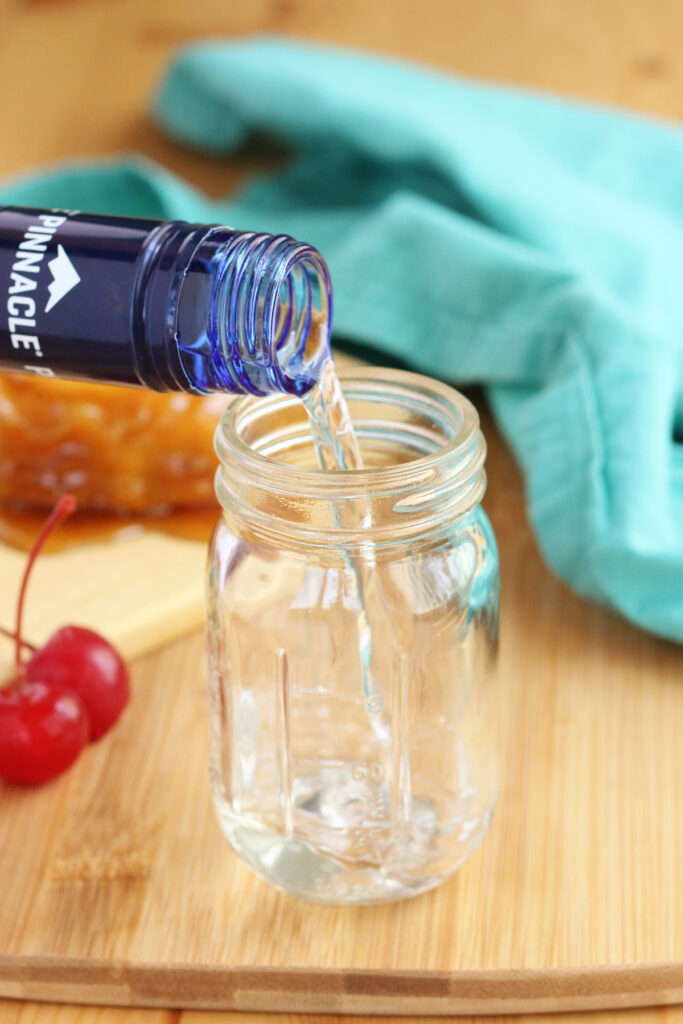 whipped vodka being poured into a glass shot glass shaped like a mason jar
