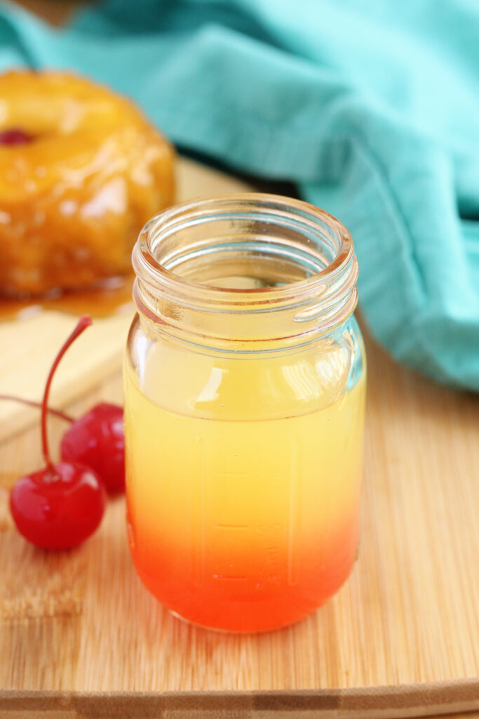 pineapple shot with grenadine on a wooden surface with cherries in the background