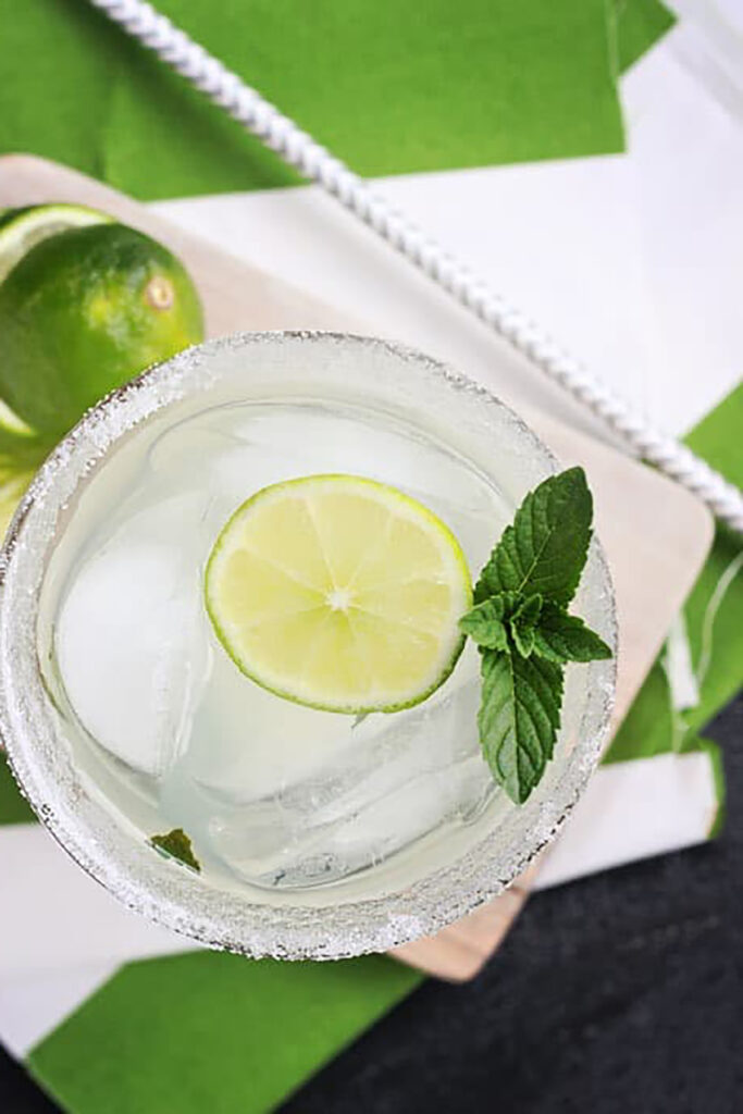 top down image of a mint limeade cocktail with a fresh mint sprig and lime slice