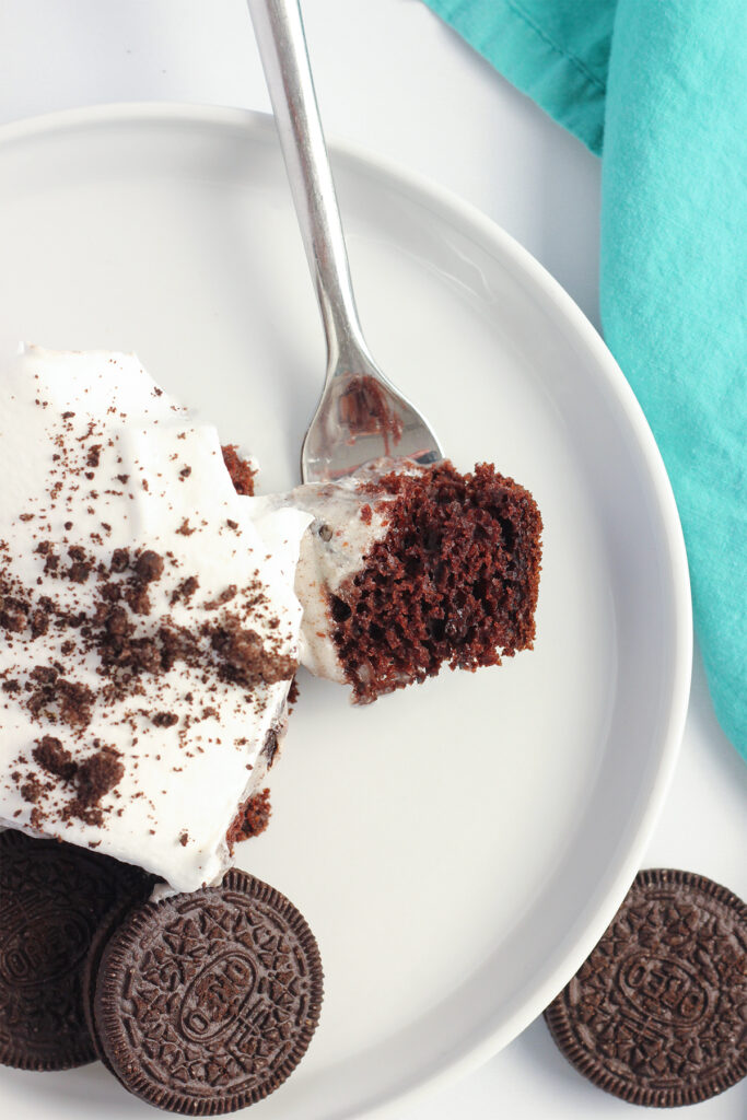 close up image of a slice of chocolate cake that has a layer of pudding and a whipped topping with chocolate cookie crumbs. 